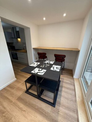 A compact kitchen with modern appliances, a dining table with four chairs, and a window providing natural light. - 3 bed house by mustang escapes (Bradley Stoke)