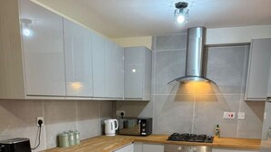 Eine kleine Küche mit weißen Schränken, einer Holz Arbeitsplatte, einem eingebauten Backofen und einer Edelstahl-Dunstabzugshaube.