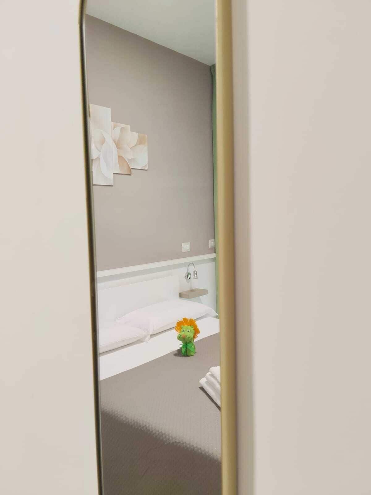 A hotel bathroom with a large mirror, a sink, and a small decorative item on the floor.