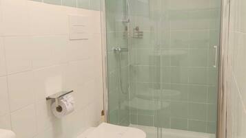 A bathroom with a toilet, bidet, and glass-enclosed shower.