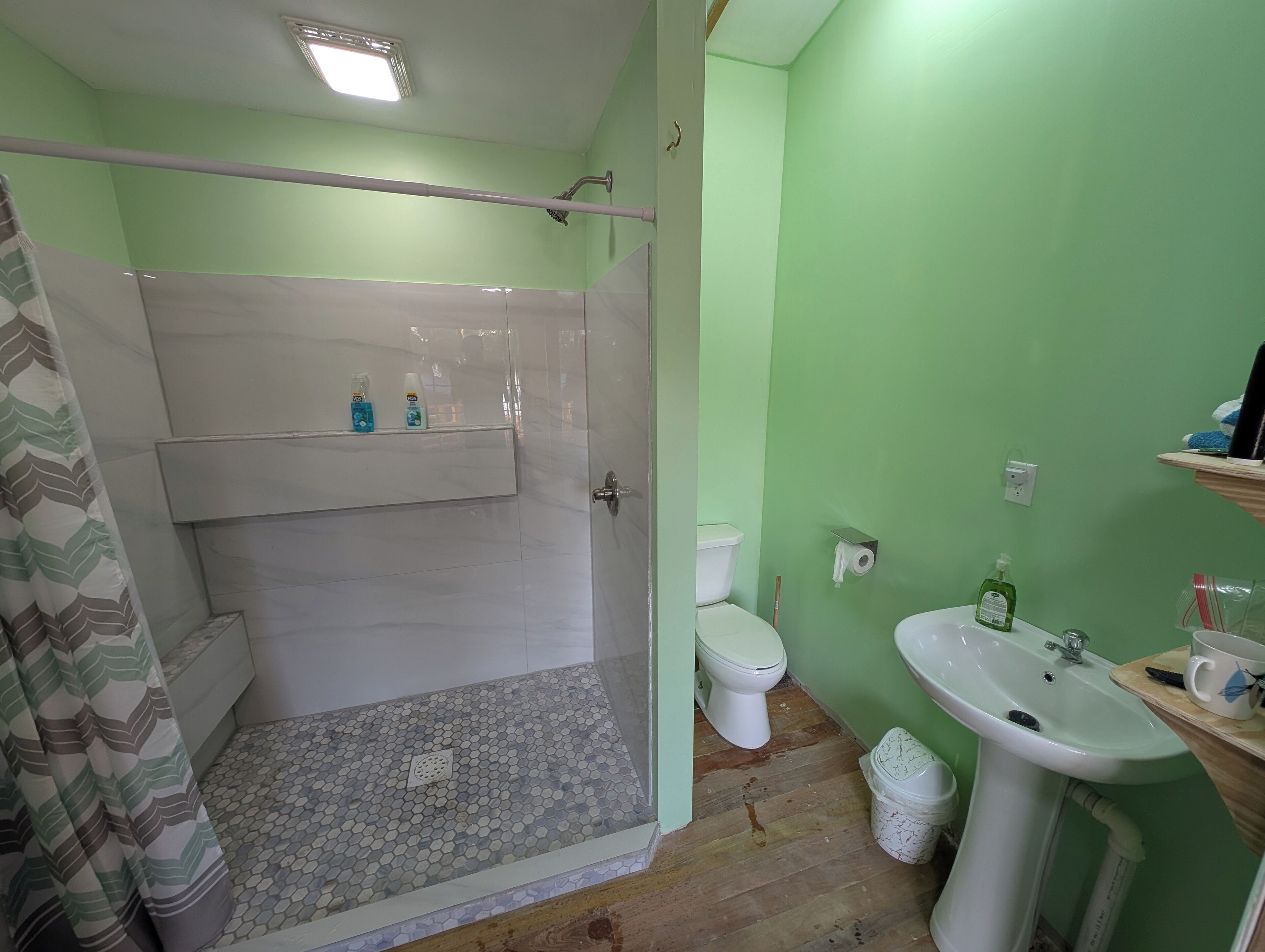 Een badkamer met douche, toilet en wastafel.