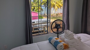 Een hotelkamer met een bed, een raam met gordijnen, een ventilator en handdoeken.