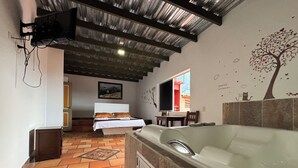 Una stanza con una vasca da bagno ampia, un letto e un'area da pranzo.