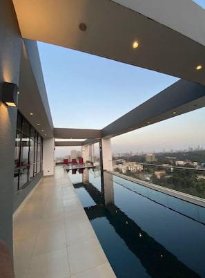 Un interior moderno con un balcón de cristal que da a una vista urbana.