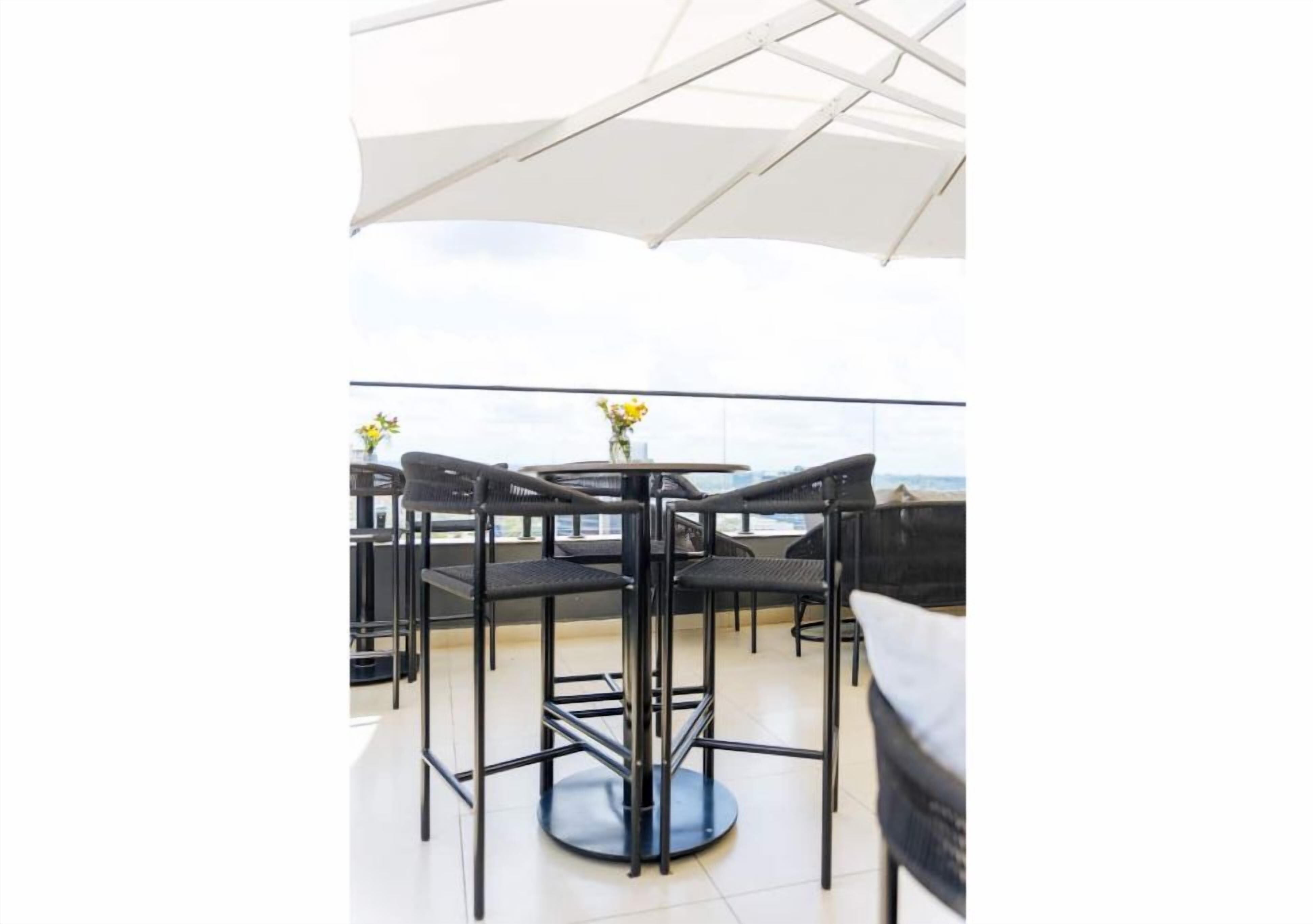 Une terrasse sur le toit avec une table ronde et des chaises, un parasol blanc et une vue sur la mer.