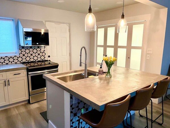 A modern kitchen with a central island, stainless steel appliances, and pendant lighting.