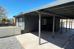 A covered outdoor area with a concrete floor, metal beams, and a gravel border.