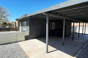 Uma área externa coberta com piso de concreto, vigas de metal e uma borda de cascalho.