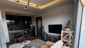 A modern living room with a sofa, a TV, and a dining area with chairs and a table.