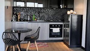 A modern kitchen with a black countertop, a round dining table, and two black chairs.
