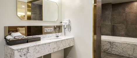 A modern bathroom with a marble sink, a hairdryer, and a large mirror.