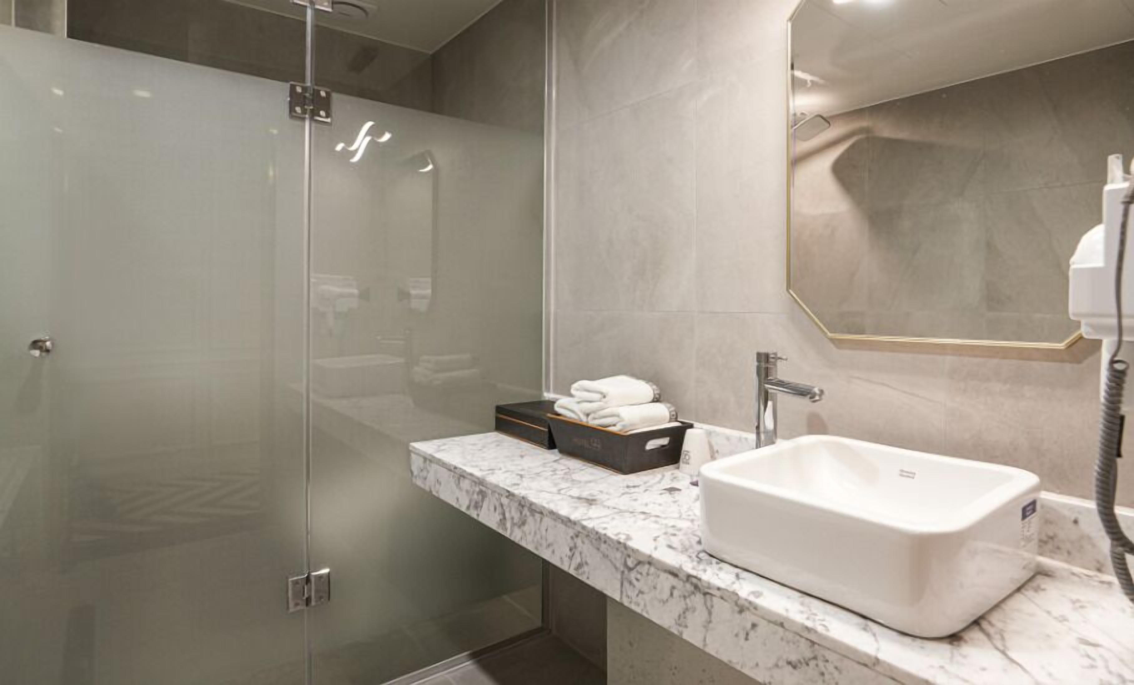 A modern bathroom with a glass-enclosed shower, a marble countertop, and a large sink.