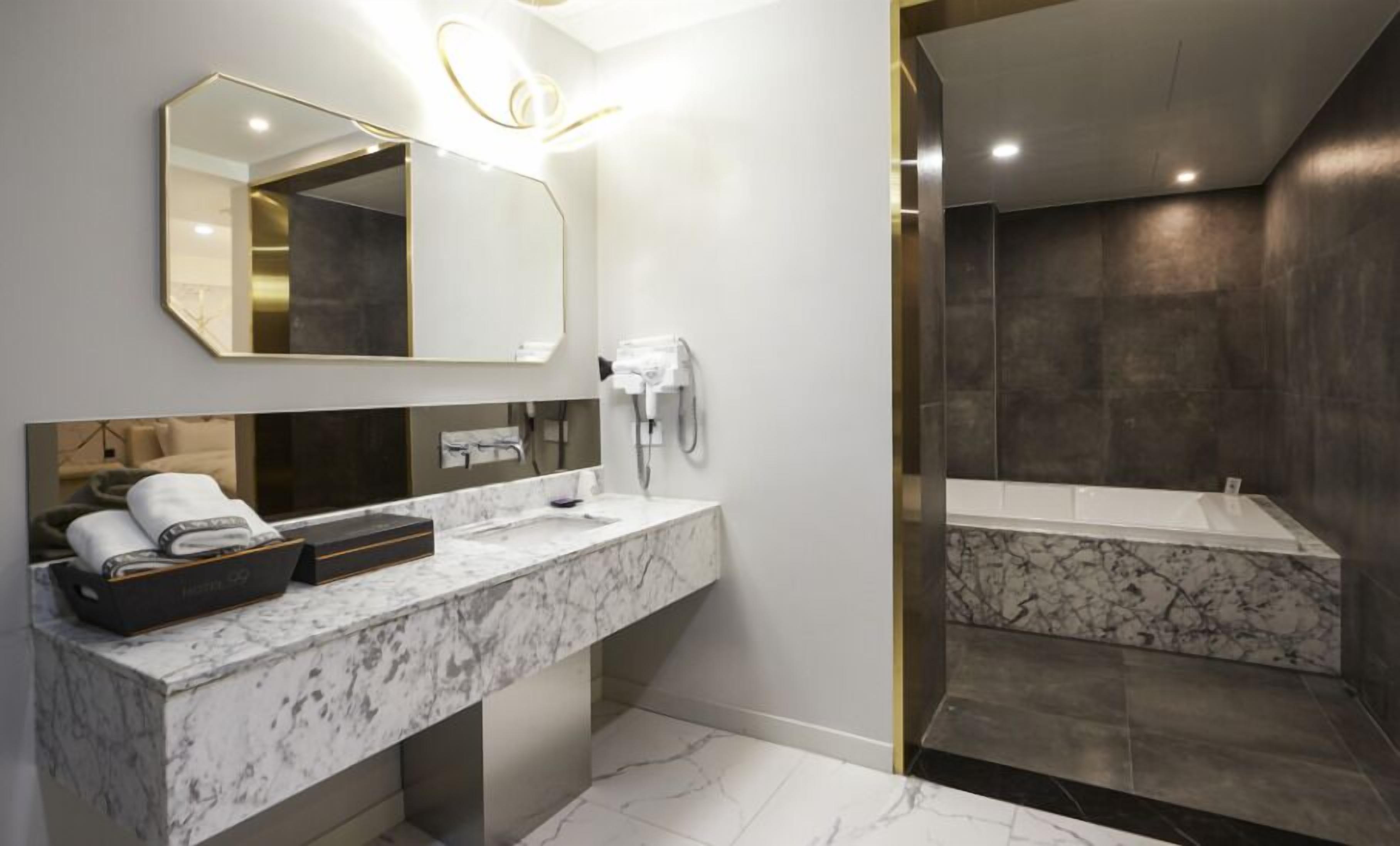 Un baño moderno con encimera de mármol, un espejo grande y una zona de ducha separada.