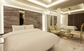 A modern hotel room with a large bed, a sitting area with a small table, and a mirror. - hotel 99 prestige (Seoul)
