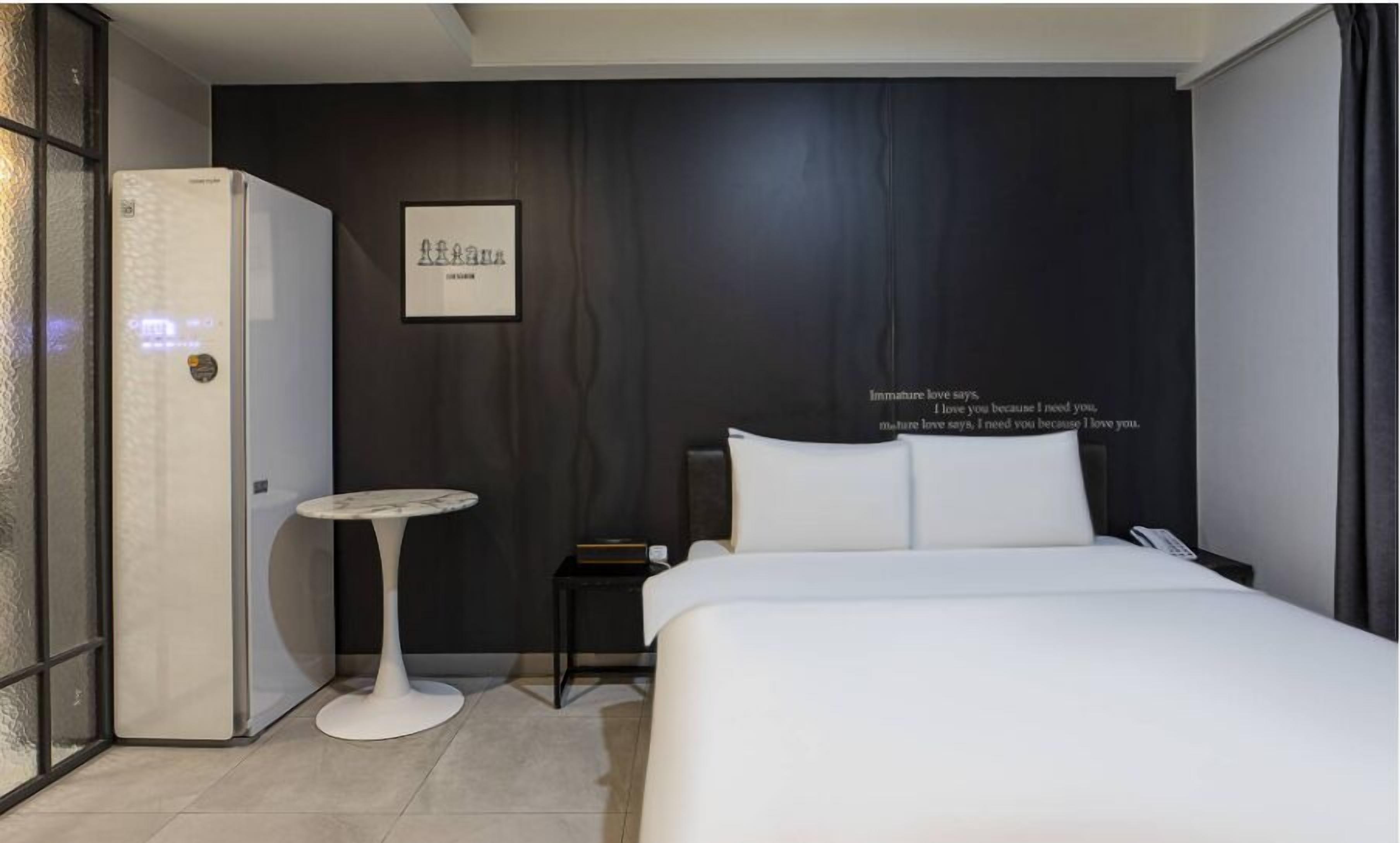 Une chambre d’hôtel moderne équipée d’un lit, d’une table de chevet et d’un réfrigérateur.