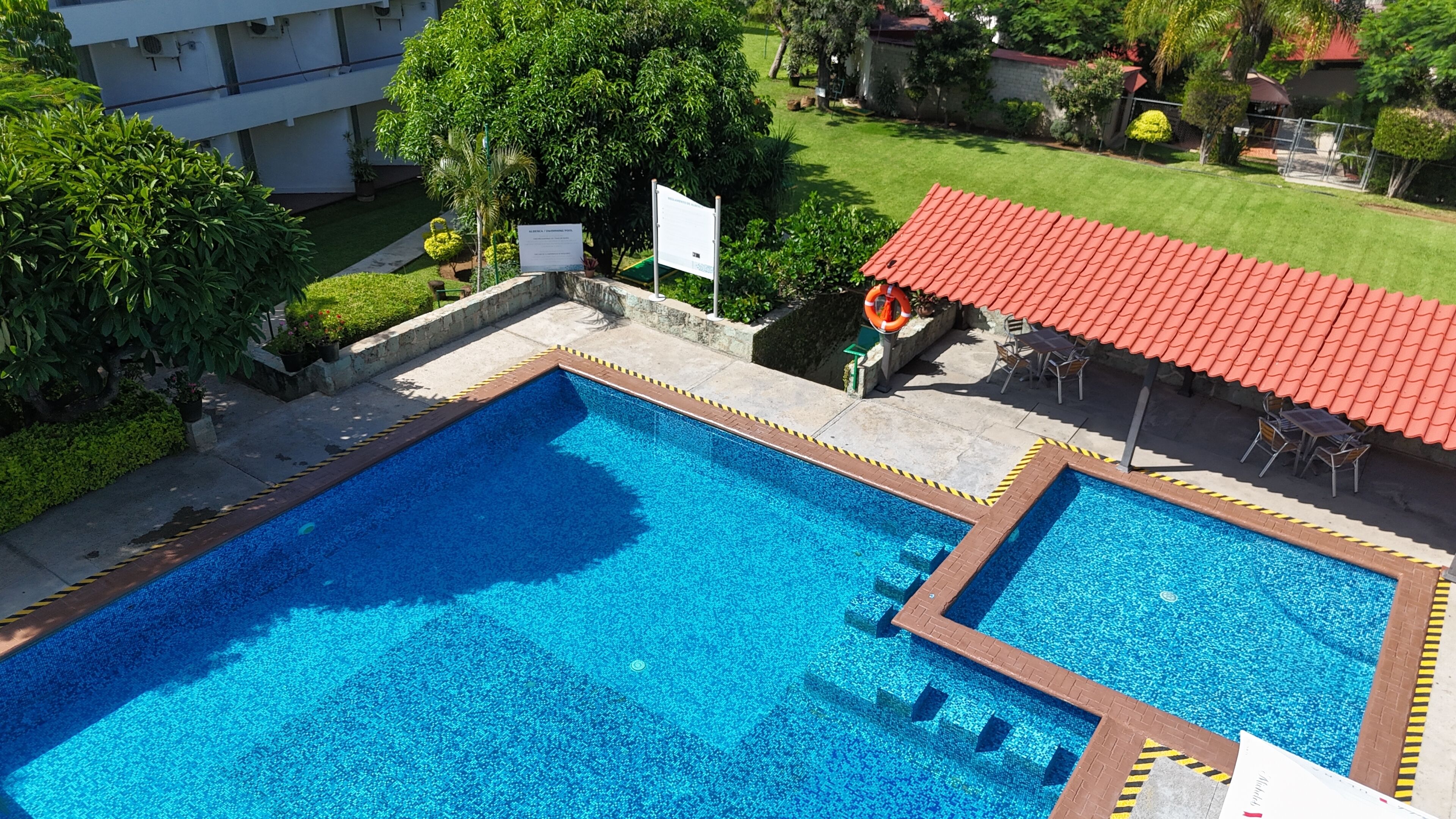 Una piscina rectangular con techo de baldosas rojas y un deck perimetral.