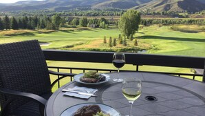 Ein Esstisch mit Speisen und Weingläsern, mit Blick auf einen Golfplatz.