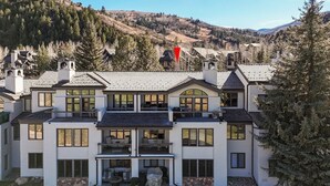 Ein modernes mehrgeschossiges Haus mit einer großen Veranda, mehreren Balkonen und Blick auf eine gebirgige Landschaft.