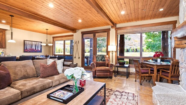 A spacious living area with a wooden ceiling, a sofa, a coffee table with magazines, and a dining table with chairs. - Deer Valley Bct-501 Hot Tub KBM Resorts (Park City)