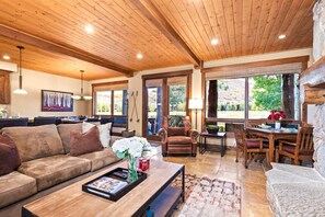 A spacious living area with a wooden ceiling, a sofa, a coffee table with magazines, and a dining table with chairs. - Deer Valley Bct-501 Hot Tub KBM Resorts (Park City)