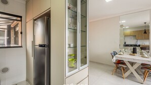 A modern kitchen with a built-in refrigerator, a glass-fronted cabinet, and a dining area with a table set for two. - Apt With BBQ 70m From the Beach - Mta0201 (Barra Velha)