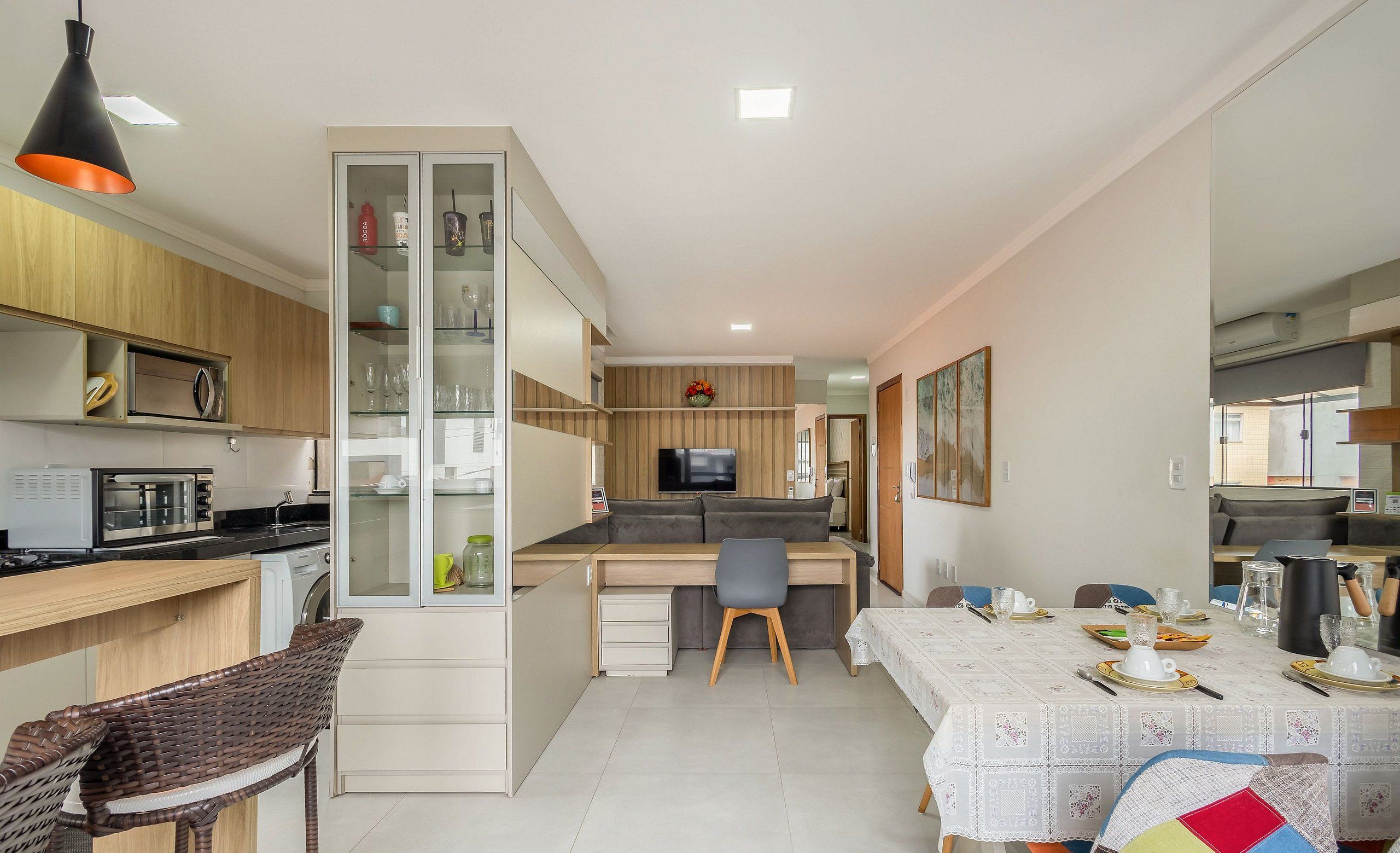 Une cuisine compacte dotée d’appareils électroménagers modernes, un coin repas avec une table dressée pour deux personnes et un espace salon confortable.