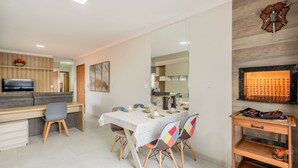 A modern dining area with a table set for four, a sofa, and a TV in the background. - Apt With BBQ 70m From the Beach - Mta0201 (Barra Velha)