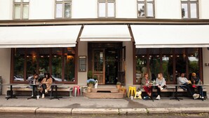 A building with a covered outdoor seating area and a wooden door.