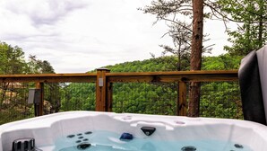 A hot tub with a wooden deck and a view of a forested area. - Biggest Deck! Beautiful Dome (Pikeville)