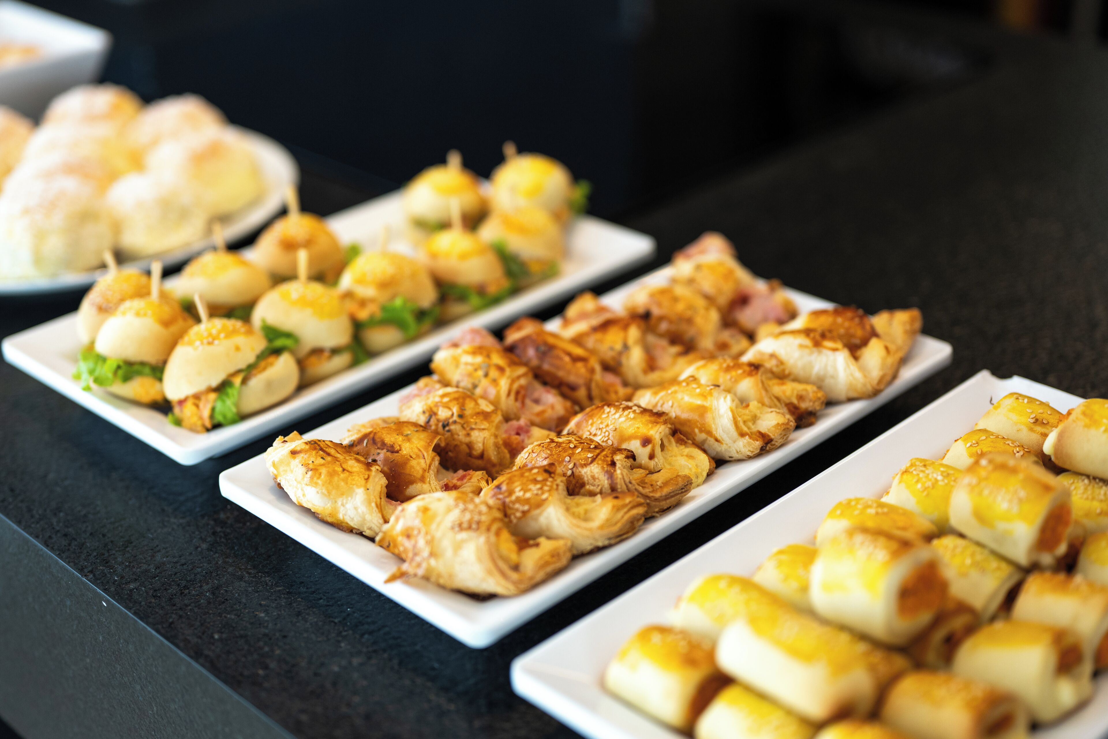 Una mesa de bufé con diversos alimentos, incluyendo pasteles y aperitivos.