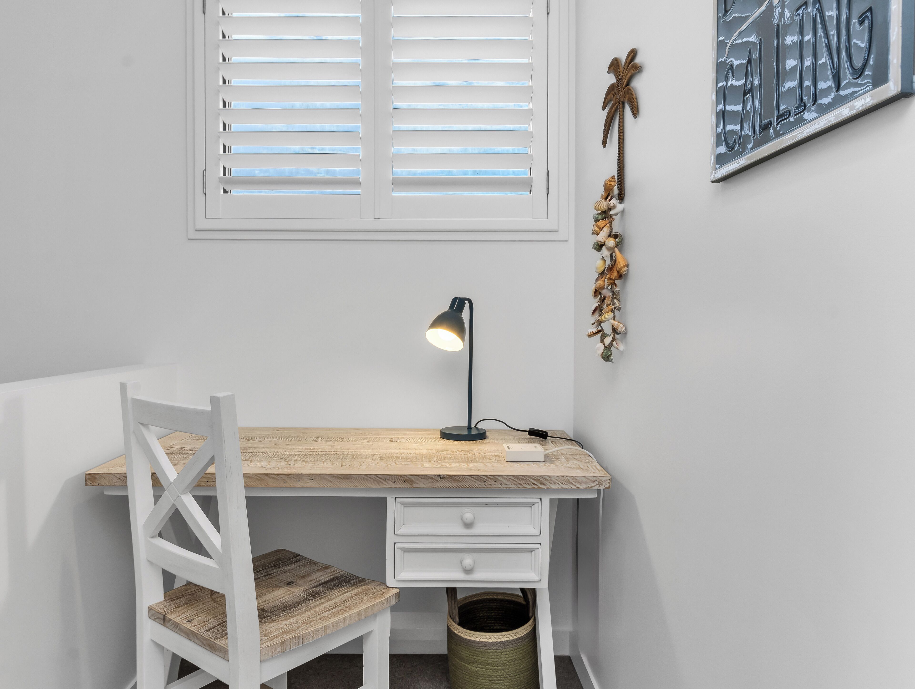 A study area with a desk, chair, lamp, and wall decorations.