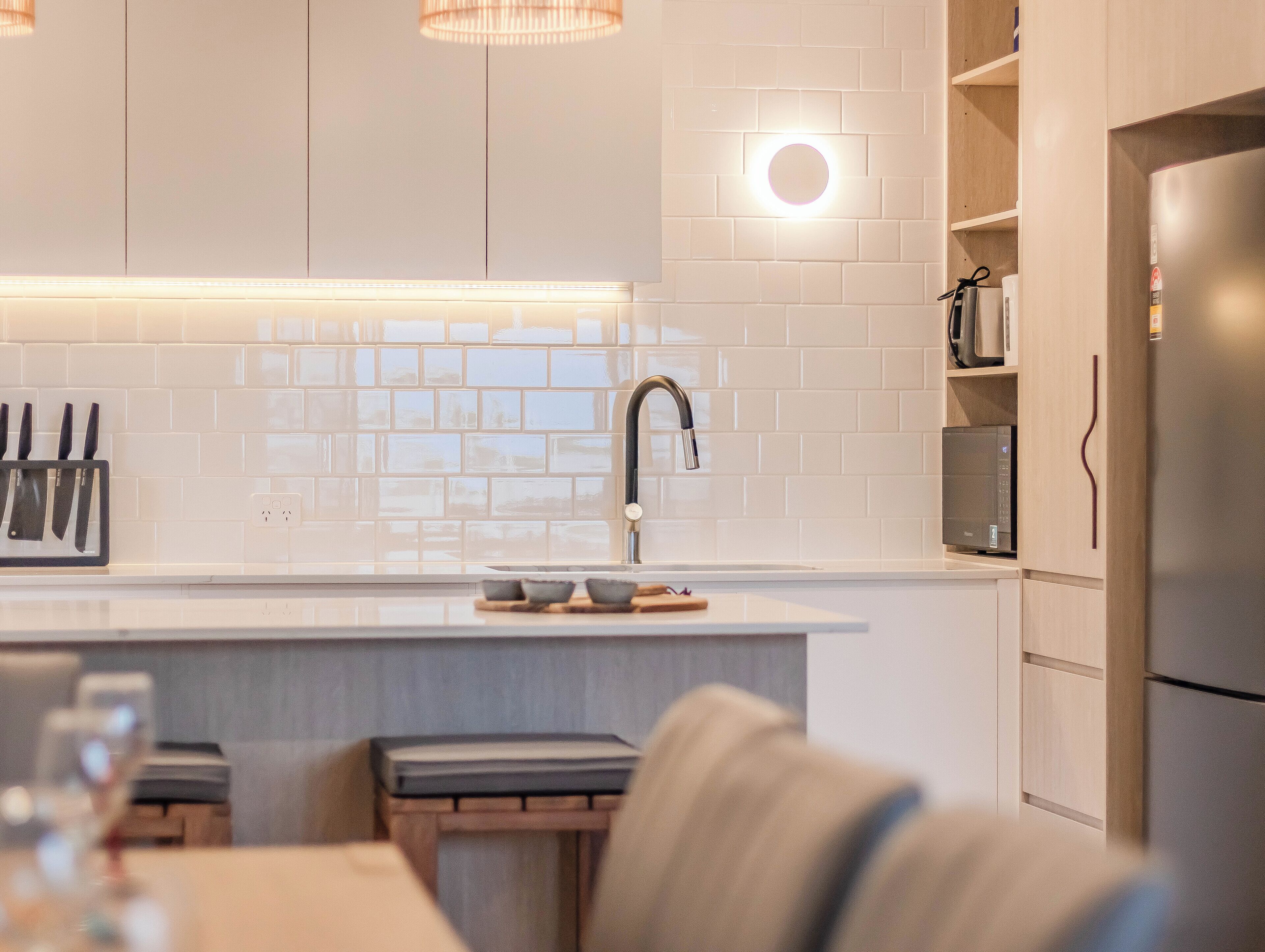 Una cocina moderna con azulejos blancos tipo metro, un lavamanos de acero inoxidable y un horno empotrado.