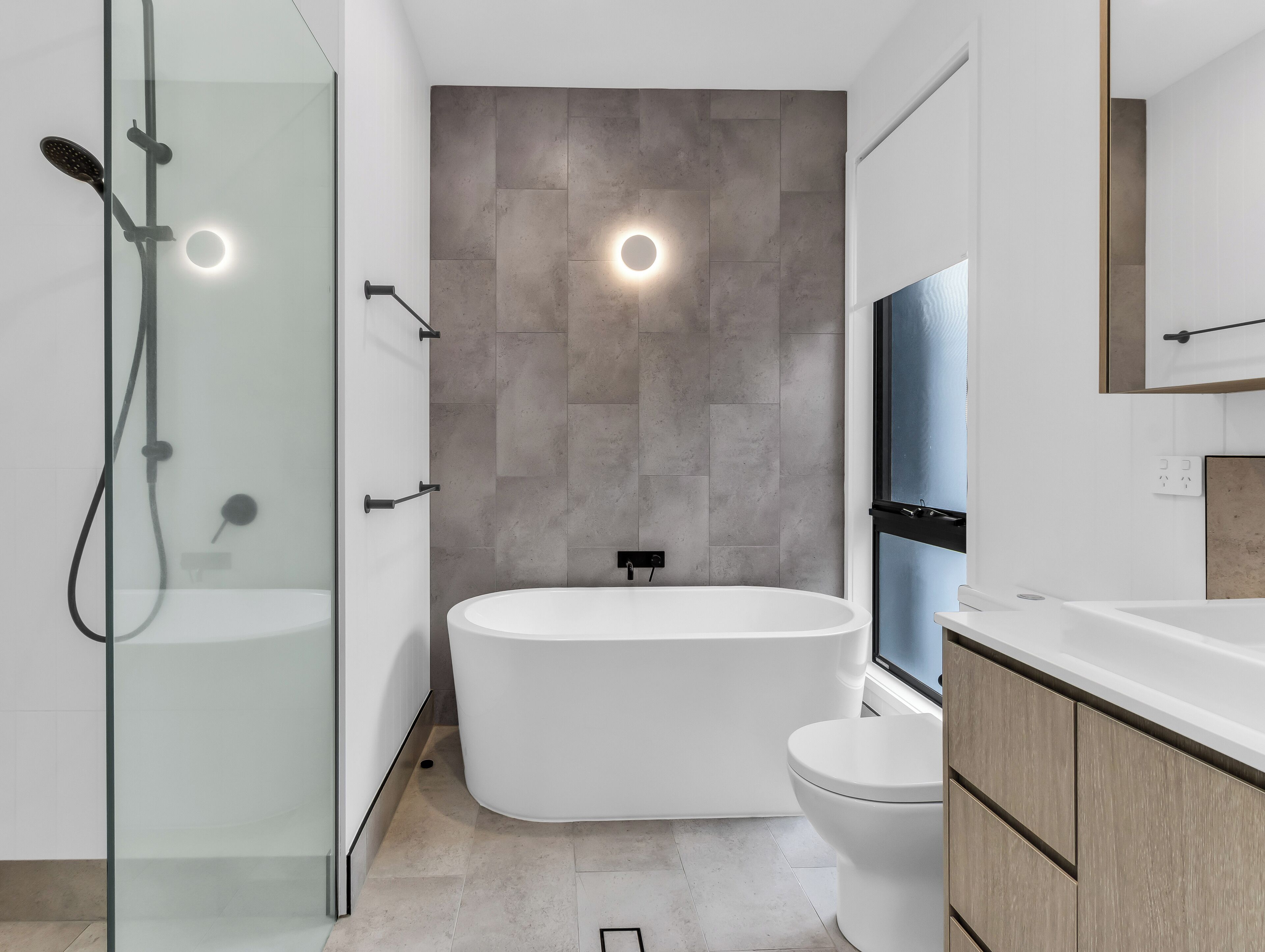 A modern bathroom with a glass shower enclosure, a freestanding bathtub, and a toilet.