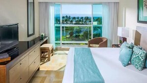 Habitación de hotel con una cama grande, televisión, escritorio y vista al océano.
