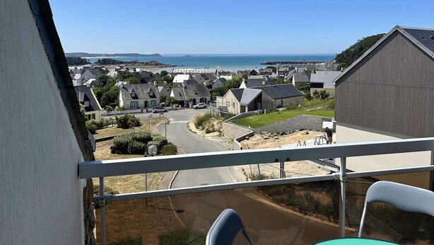 A balcony with a view of a coastal village, including houses and a beach. - Sea-view apartment in Erquy | 4 guests | Ref 600 (ERQUY)