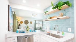 A modern kitchen with white cabinets, stainless steel appliances, and blue tile backsplash.