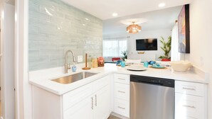 A modern kitchen with white cabinets, a stainless steel dishwasher, and a tiled backsplash.