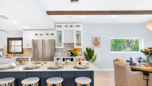A modern kitchen with white cabinets, stainless steel appliances, and a central island with stools. - Walk to Beach 5BR Wtr, Pool, Dock, Golf Cart (Indian Rocks Beach)