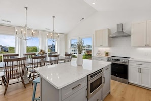 A modern kitchen with a large island, stainless steel appliances, and a view of the neighborhood.