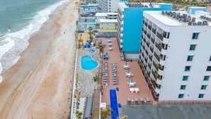 Ein Strandhotel mit Pool, Sitzgelegenheiten im Freien und Blick auf den Ozean.