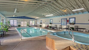 An indoor swimming pool with multiple lanes, lounge chairs, and potted plants.