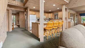 Une cabane en bois spacieuse comprenant une cuisine centrale, un coin repas et un espace salon confortable.