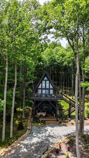 A cabin with a balcony, surrounded by trees.