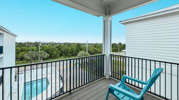 Een balkon met uitzicht op een zwembad en omliggend groen.