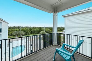 A balcony with a view of a swimming pool and surrounding greenery. - Seaview Cottage | Gulf Shores | Walk to The HangOut | My Beach Getaways (Gulf Shores)