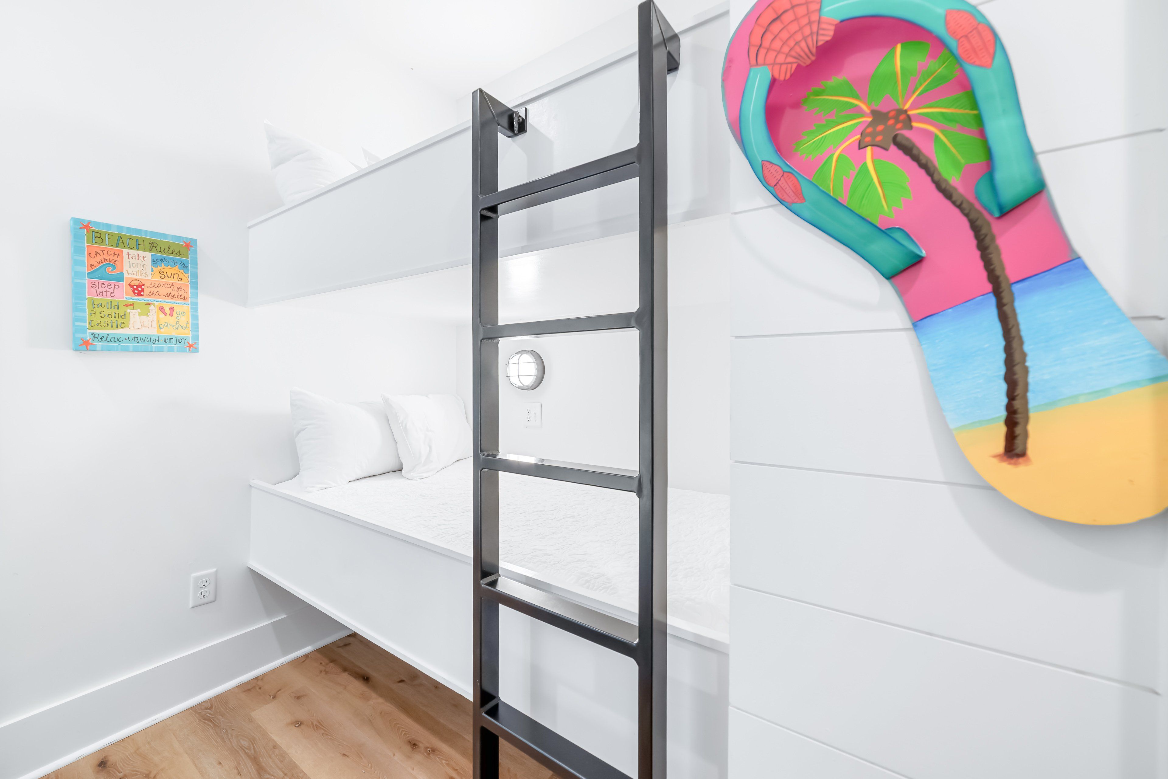 Een stapelbed met een ladder, een kleurrijke wandversiering en een klein poster aan de muur.