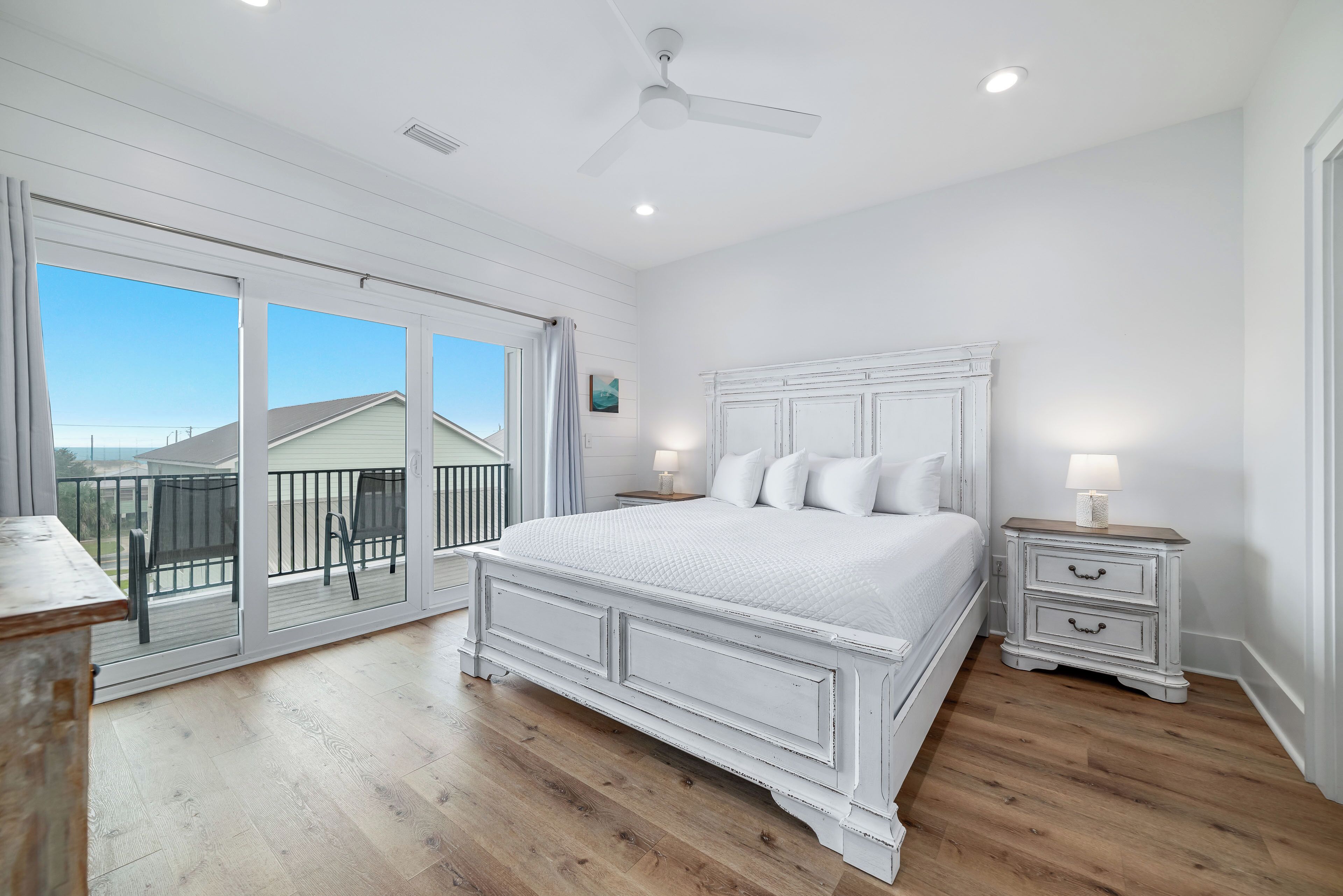 Une chambre dotée d’un grand lit, d’un ventilateur de plafond et d’un balcon aménagé avec du mobilier d’extérieur.