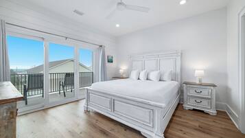 Une chambre dotée d’un grand lit, d’un ventilateur de plafond et d’un balcon aménagé avec du mobilier d’extérieur.