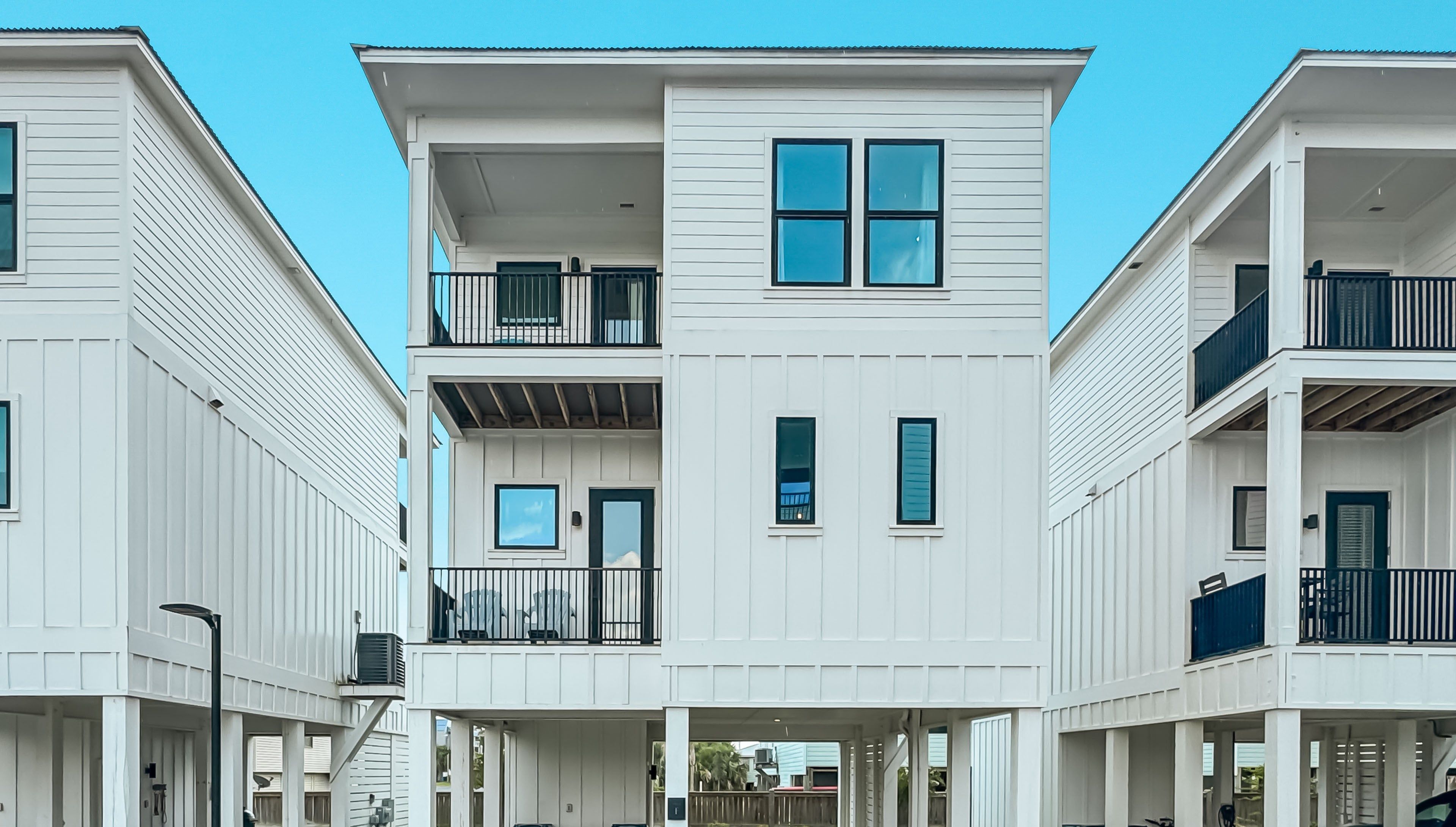A multi-story residential building with balconies, a covered entryway, and a clear sky.