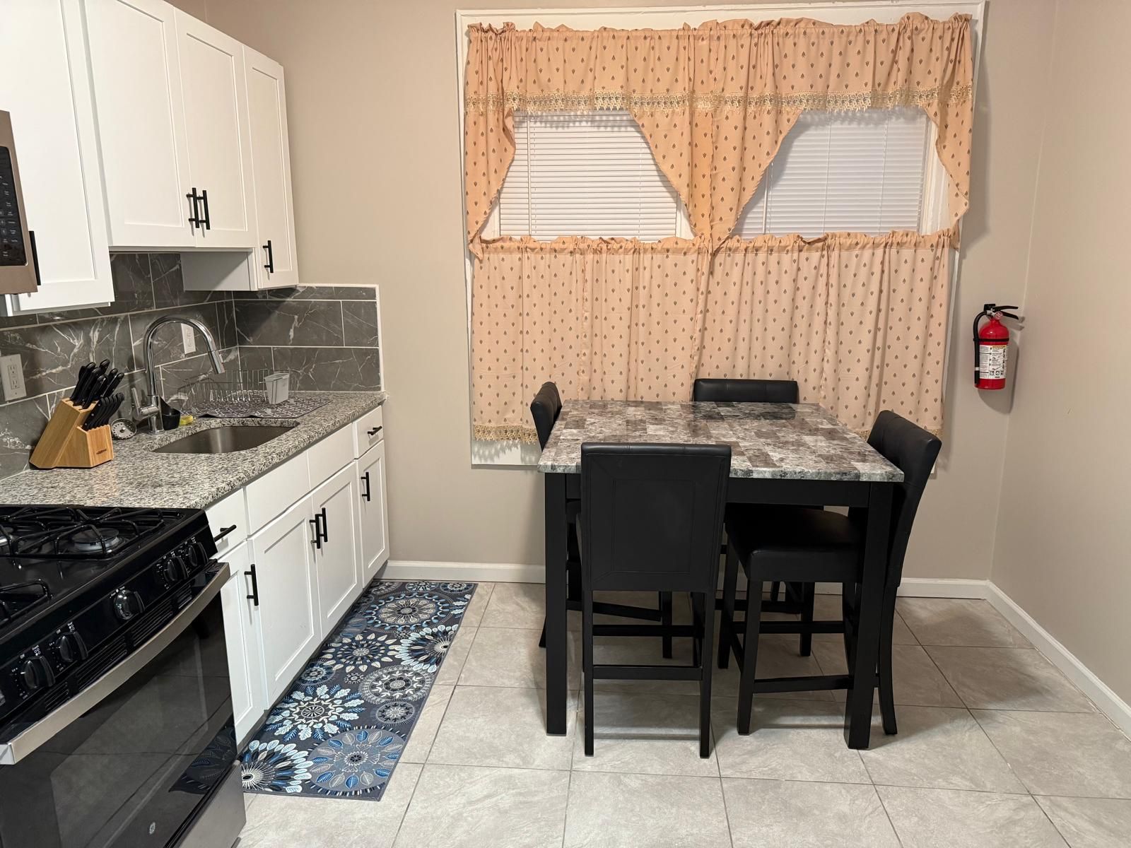 A compact kitchen with a gas stove, sink, and white cabinets.